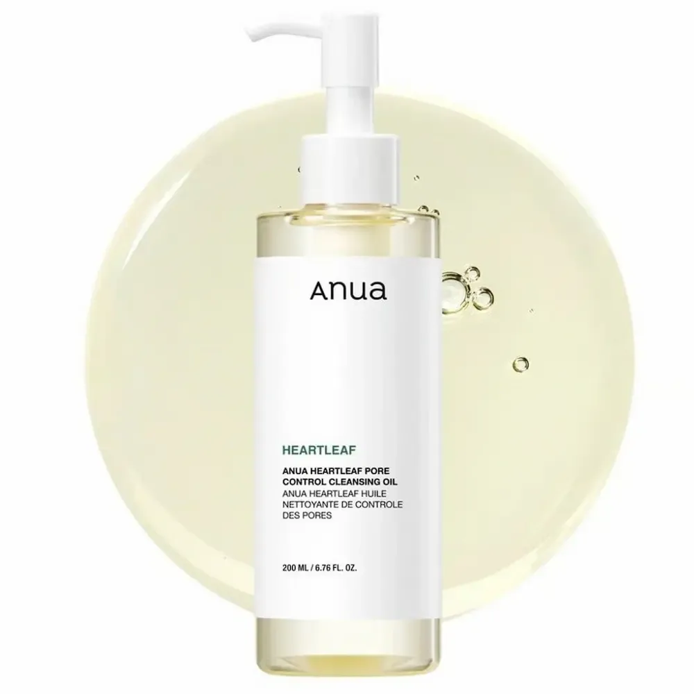A 200 ml pump bottle of Anua Heartleaf Pore Control Cleansing Oil, standing on a pool of pale yellow oil.